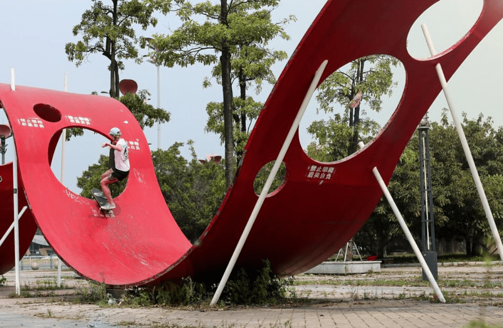 Sarah on famous red ribbon sculpture on her skateboard